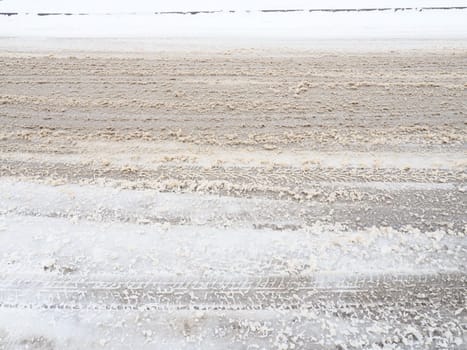 Snowdrifts on the side of the road. Bad weather and traffic. Snow on asphalt. Difficult driving conditions. Winter slosh on the road. Braking distance of a car