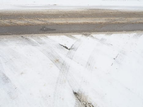 Snowdrifts on the side of the road. Bad weather and traffic. Snow on asphalt. Difficult driving conditions. Winter slosh on the road. Braking distance of a car