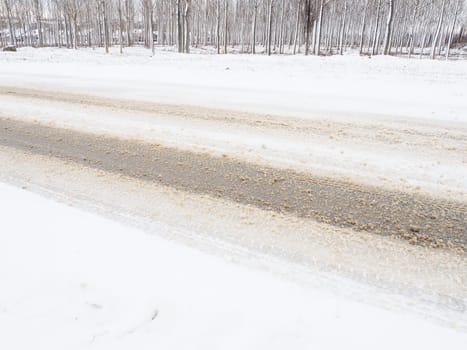 Snowdrifts on the side of the road. Bad weather and traffic. Snow on asphalt. Difficult driving conditions. Winter slosh on the road. Braking distance of a car