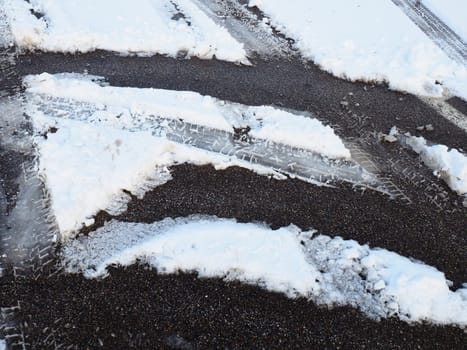 Snowdrifts on the side of the road. Bad weather and traffic. Snow on asphalt. Difficult driving conditions. Winter slosh on the road. Braking distance of a car
