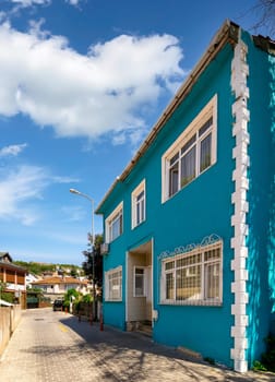 Cobblestone alley, with beautiful old traditional houses, including blue house, suited in Anadolu Kavagi district, Istanbul, Turkey, in a summer day