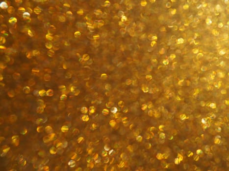 Bokeh light of gold glitters. Golden glitter texture background. Sparkling glitter wrapping paper with sequins and sparkles. Festive golden bokeh and glitter. Beautiful macro background.