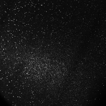 Black bokeh texture on black background. White glitter or illuminated dust.