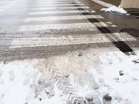 Snow, ice, slush and winter mud at a pedestrian crossing. The air temperature is about 0. Difficult driving conditions. Braking distance of the car. Traffic Laws. Infrastructure and road services.