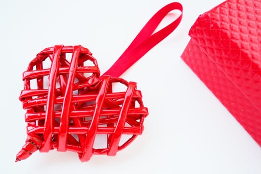 Red braided heart with a silk ribbon on a white background. Valentine's Day. Red gift box. copyspace. Flat lay.