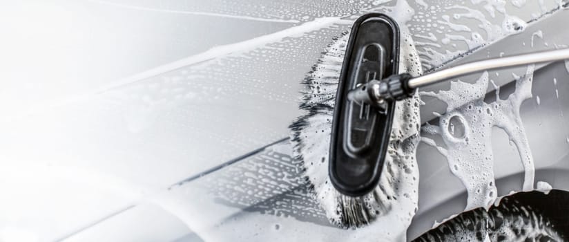 Brush leaving strokes in shampoo and foam. Space for text on the left, self service carwash banner.
