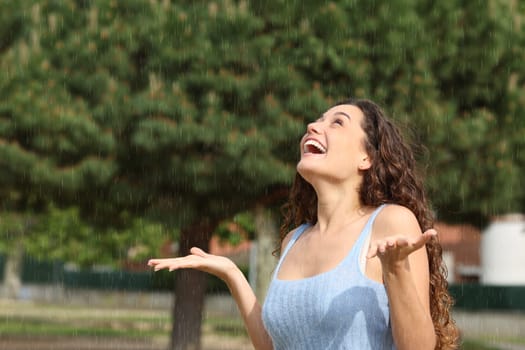 Excited woman under the sudden rain looking up
