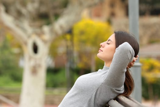 Side view portrait of a woman relaxing in a bench