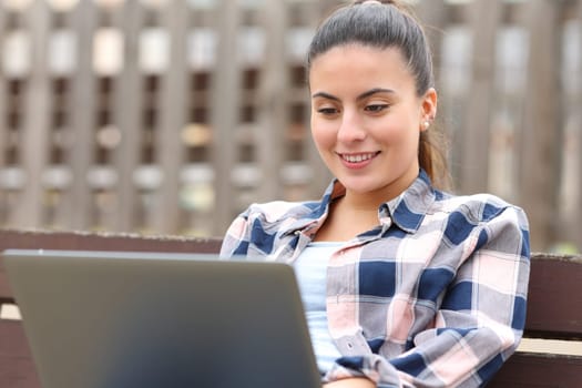 Teen using laptop sitting in a bench