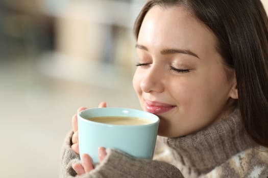 Satisfied teen smelling coffee at home
