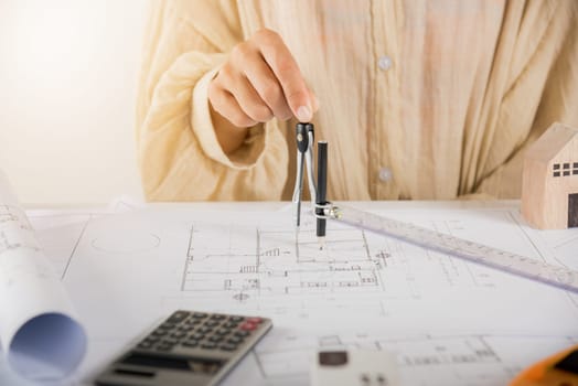 Architect interior design drawing with divider compass on house plan blueprint paper for editing on table desk at architecture office, Engineer sketching construction, Architectural project workplace
