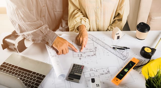 Two engineers pointing at drawings project, Architect team meeting consult and work for architectural construction project working with partner and engineering after editing on blueprint paper plans