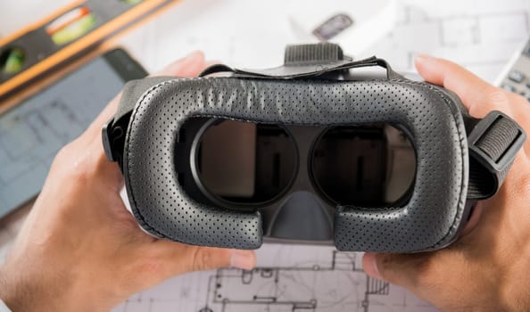 Architectural building design hold back 3D VR glasses and construction plans with blueprints paper project plans, designing man edit building or architecture, technology industry, Architect workplace