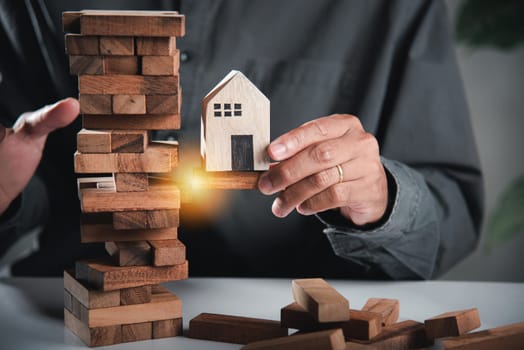 Alternative risk plan. Business hand playing tower wooden blocks game, man pull one wood block from tower he clenched his fist, show great joy in accomplishing it, Business gambling growth concept
