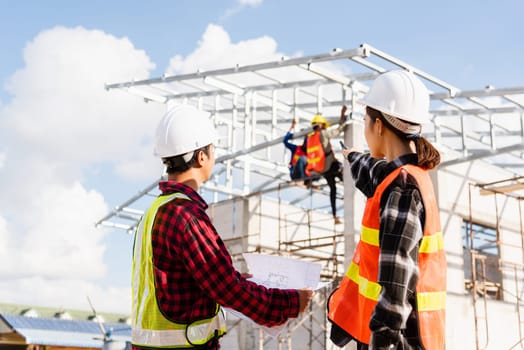 Back two architect and client discussing help create plan with blueprint home building at construction site. Asian engineer foreman worker man and woman meeting talking on drawing paper project