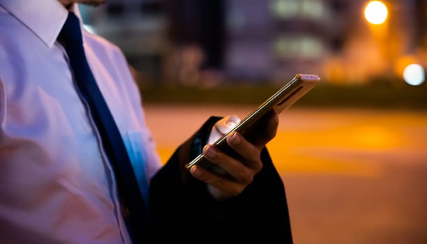 Young man walking and chatting on mobile phone with friends at social networks outdoor, Portrait Asian businessman typing an sms message via smartphone after work near office at night city street