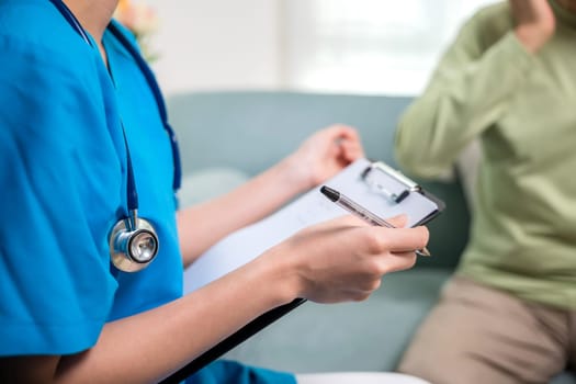 Asian young nurse writing prescription during home visit sick elder old man, Senior man takes doctor at home telling about health complaints, health care and medical concept