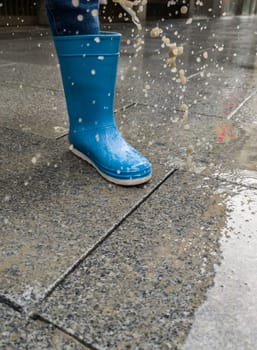 A loose cobblestone splashes on a childs boots when stepped on. High speed shooting