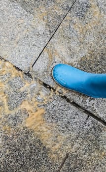 A loose cobblestone splashes on a childs boots when stepped on. High speed shooting