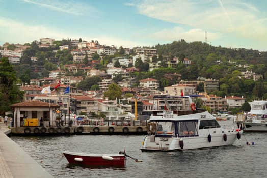 Istanbul, Turkey - August 31, 2022: Green mountains of the European side of Bosphorus, with traditional houses, and dense trees, at Bebek district, with docked boats at Bebek Iskelesi in the front