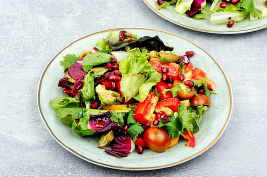 Vitamin salad with greens, pepper, red lettuce and cucumber, decorated with pomegranate.