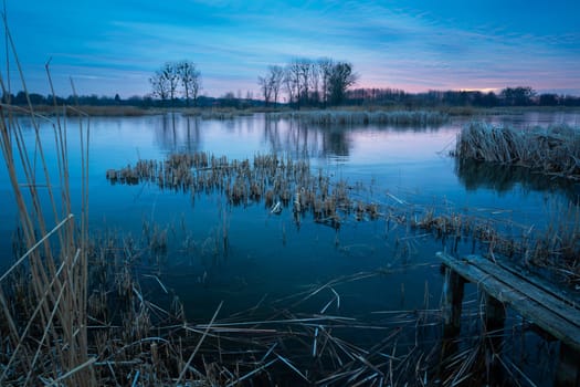 A frozen lake and an old wooden bridge, evening view