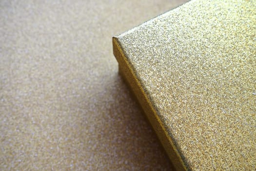 Golden gift box on a golden background. Decorative surprise box. Copy space.