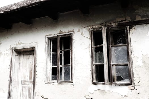 Abandoned spooky old house. Wooden windows and doors. The hut is a mud hut. Samani house. White stucco plaster. Halloween theme. Aging, loneliness, departure, war and devastation. Ukraine, Donbass.