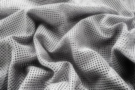 Synthetic fabric with holes laid in waves. Beautiful drape. Fabric for curtains, interior design, and decor. Wrinkled gray fabric