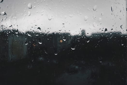bad weather in the city. Buildings, houses, cars outside the window. Cloudiness cumulus clouds. Meteorology and weather forecast. Raindrops run down the glass. Storm and Storm and wind on city streets