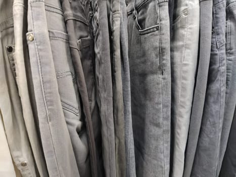 Clothes hung on hangers. Assortment of second hand store. Clothing hanging on a rack, ready for sale to customers. Saving money in crisis. Cheap shopping. Jeans and pants