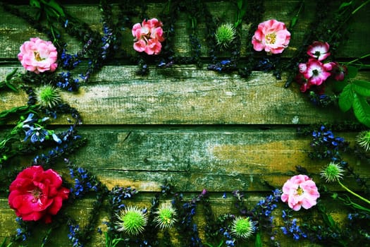 Flowers in a circle on a wooden background. Postcard for the holiday. Roses, geraniums, lavender, sage and hairy chestnuts are placed along the edges on dark boards. Background copy space, flat lay