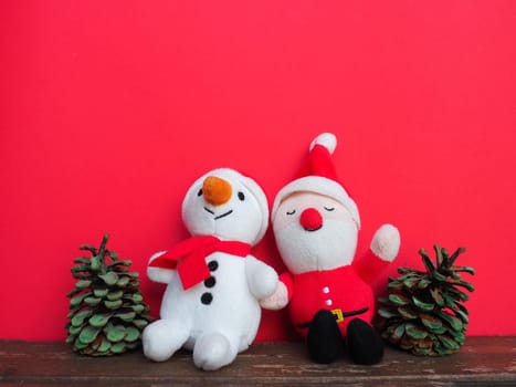 Plush sewn Christmas soft toys on a red background. Painted cones. A little smiling snowman and a funny Santa Claus. New Year's Eve and Christmas. Copy space. Cute kind children's toys