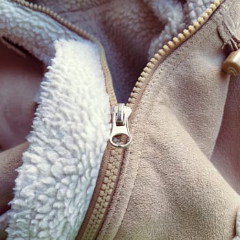 Suede outerwear. Overhead loops for buttons. Open zipper. Beige faux suede with sheepskin on the fold of a demi-season garment. seams in the material. Clothing industry and fashion