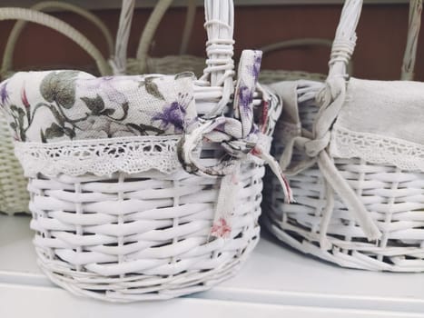 Wicker decorative baskets on a shelf in a store. Pretty baskets painted white. Textile bag. Stylish gift for Easter. Decor element of the interior of an apartment, a country house or a spring garden