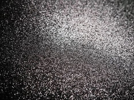 Black glitter texture christmas background. Bent shiny velvet paper.