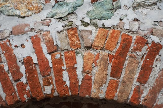 Brick wall of an ancient fortress. Uneven red and brown bricks with cement. Brick background
