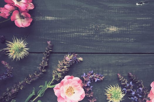 Flowers in a semicircle on a wooden background. Postcard for the holiday. Roses, lavender, sage and hairy chestnuts along the edges on dark boards. Background copy space, flat lay. Festive poster
