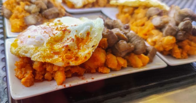 Scrambled potatoes with fried egg and tenderloin. Served at tapas bar desktop