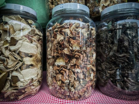 Large glass jars full of Dried Mixed Wild Mushrooms. Selective focus