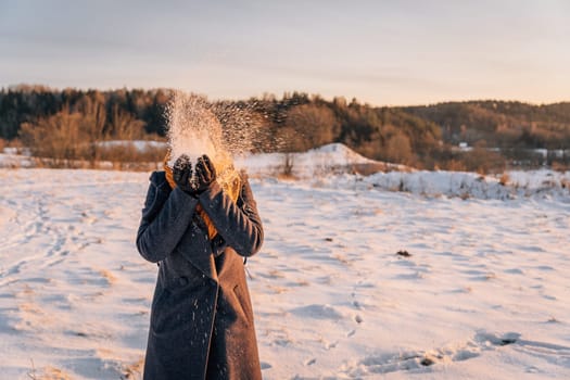 Faceless winter portrait of a woman tossing snow.