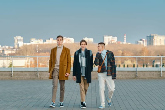 Three young men in autumn clothes are walking down the street