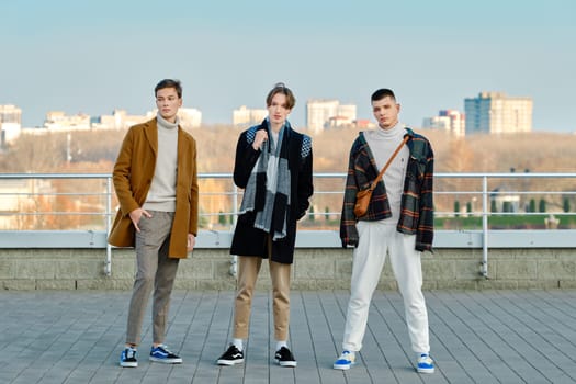 Three young men in autumn clothes standing on the street