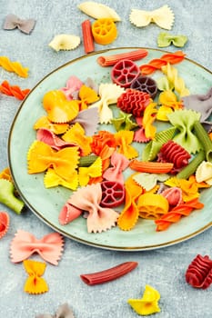 Colorful italian raw pasta on plate. Different types of Italian pasta. Space for text