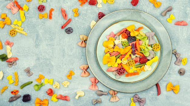 Colorful italian raw pasta on plate. Different types of Italian pasta. Space for text