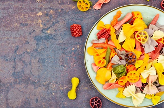 Colorful italian raw pasta on plate. Different types of Italian pasta. Space for text