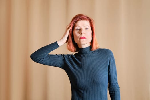 Casual portrait of middle age woman touching her red hair