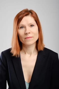 Closeup portrait of middle aged woman in suit  over grey background