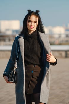 Young woman in warm coat and sweater on the street