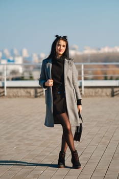 Young woman walking along the street in sunny day in spring-autumn casual outfit